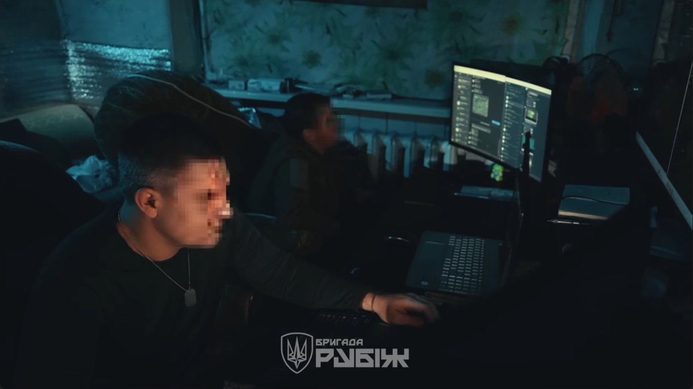 An operator monitors multiple displays at a command station. Teams track both friendly positions and enemy drone activity, coordinating electronic countermeasures across the entire operational sector.